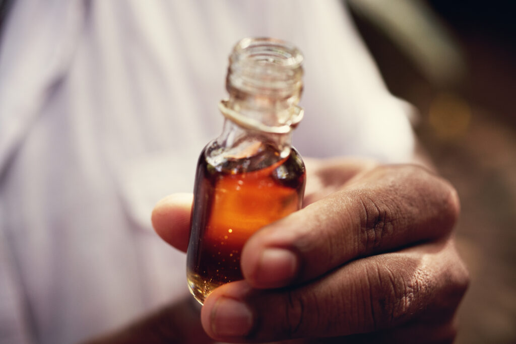 A close-up of a jar of vanilla extract in the hands of a man in the jungle of Sri Lanka.