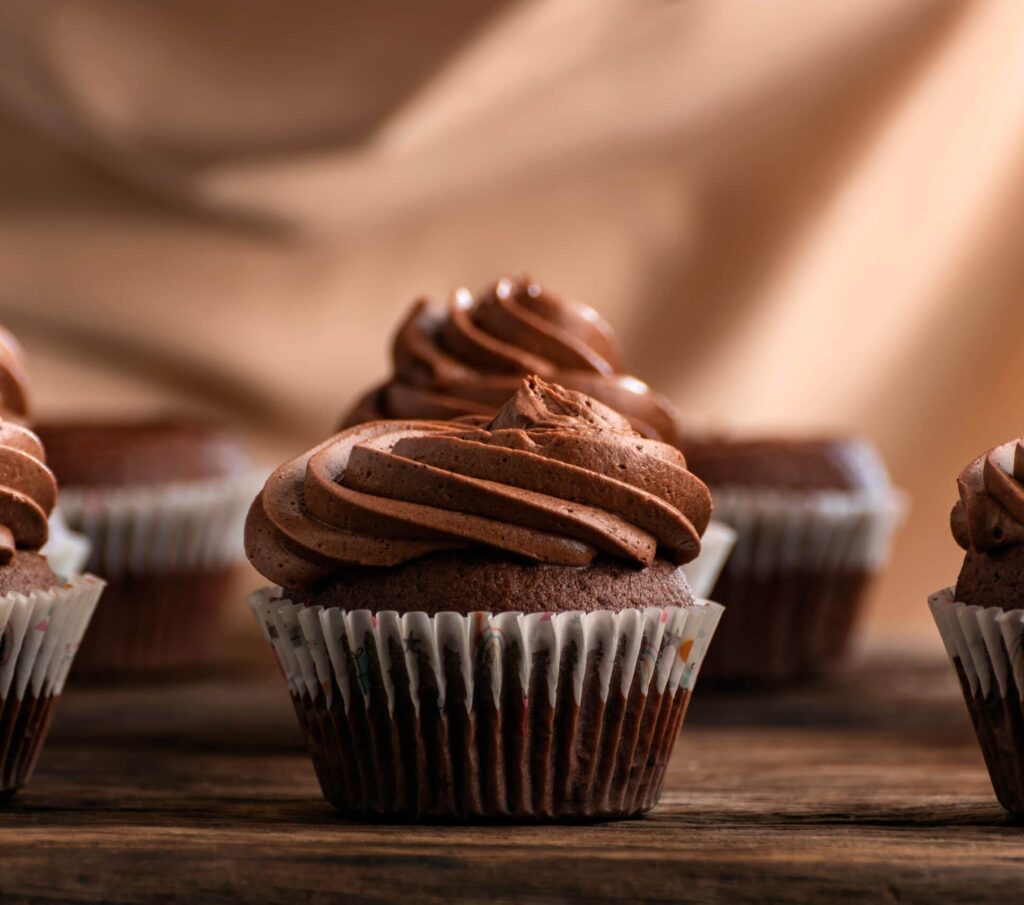 Chocolate Cupcakes With Butter Cream Tops On Wooden Table.